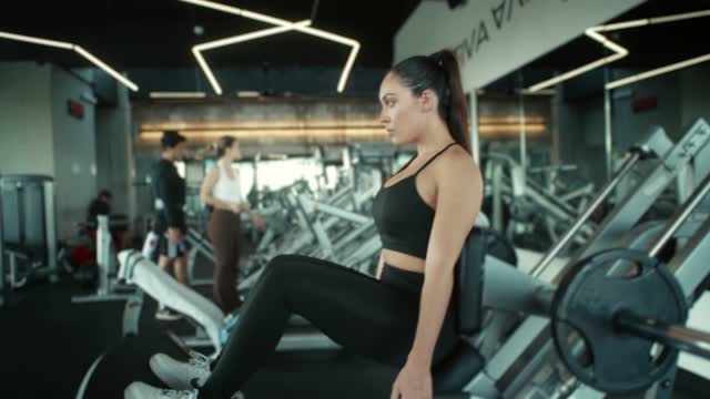 Woman exercising on a leg press machine in a modern gym.