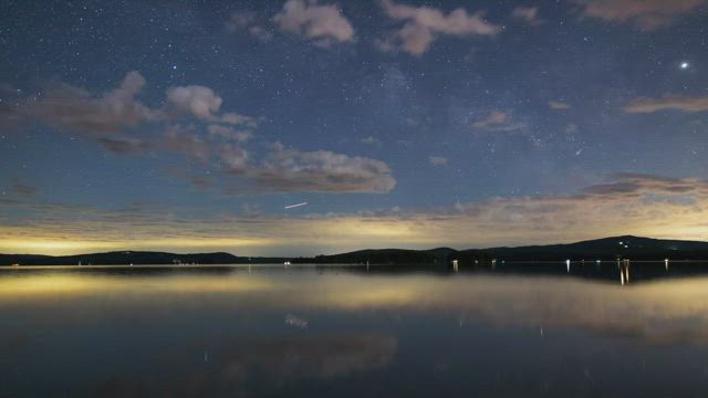 Night sky with stars at a calm lake, time lapse.
