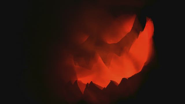 Scary Halloween pumpkin lit up in the dark.