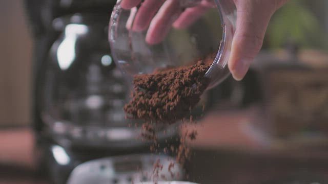 Coffee powder being poured on the coffee maker filter.